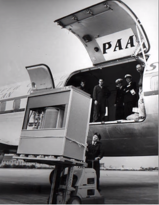 A 50's era big hard-drive being downloaded from an airplane.